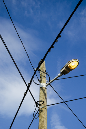 view of an electric pole with street light over a blue skyの写真素材