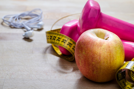 still life and close up with apple, pink weight, yellow tape measure. fitness and lifestyle concepts.の写真素材