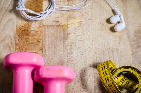 still life with pink weights and  yellow tape measure and earphone from above point of view. fitness. sport. concept.の写真素材