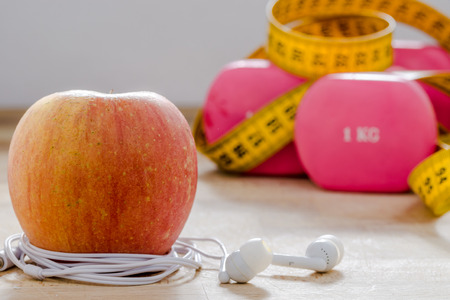 still life and close up with apple, pink weight, yellow tape measure. fitness and lifestyle concepts.の写真素材