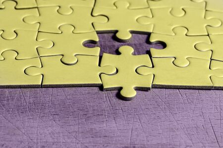 white jigsaw/puzzle with one piece at wrong position, over  black wooden table background, symbol of problem solving and new visionの写真素材