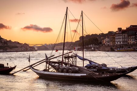 boat with port wine barrel over the douro river at sunset in porto. portugal. summerの写真素材