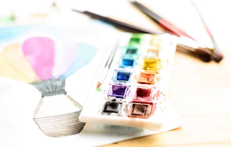 paint palette and paintbrushes and a watercolor painting on paperの写真素材