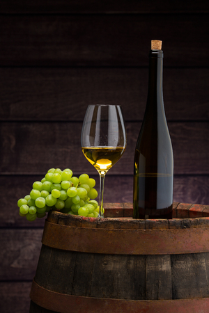white wine bottle and wine glass on wodden barrelの写真素材