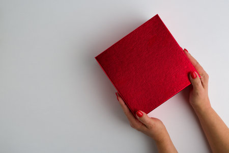 Flat lay woman holding gift wrapped and decorated with bow on blue backgroundの写真素材