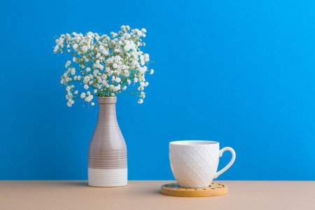 Small white flowers on a blue background. White flowers in a vase. coffee cupの写真素材