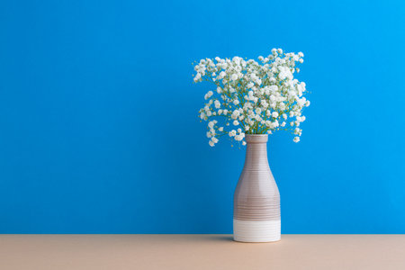 Small white flowers on a blue background. Soft home decor. Gypsophila flowers. White flowers in a vase.の写真素材