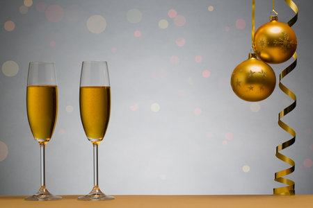 photo of two champagne glasses on brown table with Christmas ball, backgroundの写真素材