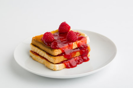 Toast bread with raspberry jam on plate isolated on white backgroundの写真素材