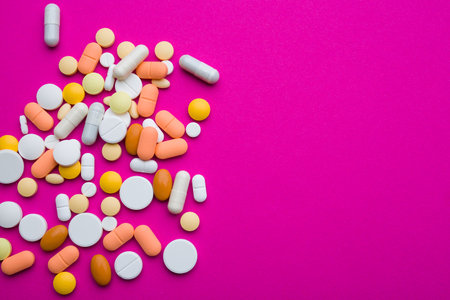 Assorted pharmaceutical medicine pills, tablets and capsules on magenta background. Copy space for textの写真素材