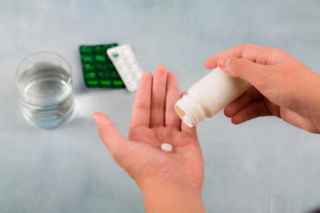 close up hand man taking pills take a medicine, cup glass of water on table. Stop drug use Taking Medication health care medical concept.の写真素材