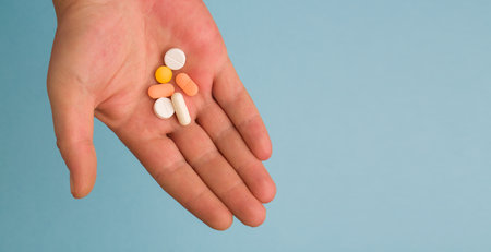 Woman's hand with falling medical pills isolated on pastel blue background. Creative close up pharmacy or health care concept. Medical treatment for disease flu virus.の写真素材