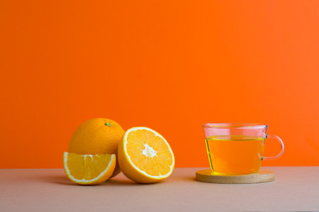 A front view of orange decorated with tea in orange backgroundの写真素材