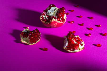 Pomegranate fruit with seeds and hearts on a purple backgroundの写真素材
