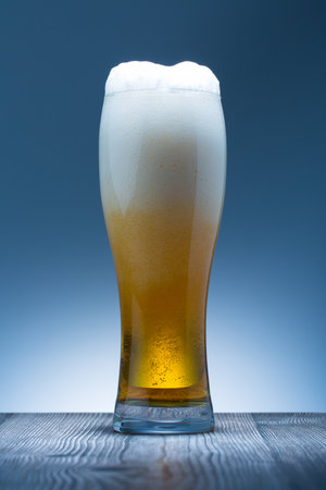 Glass of beer on a wooden table with blue background. Studio shot.の写真素材