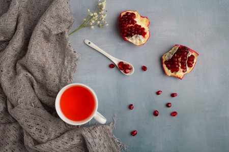 Cup of tea with pomegranate seeds on gray backgroundの写真素材