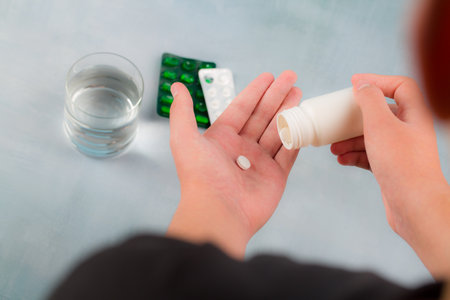 Close-up of female hands holding pills and a glass of waterの写真素材