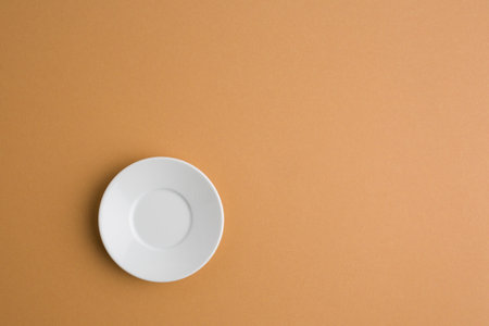 Empty ceramic round plate on brown background with clipping path. View from aboveの写真素材