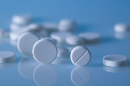 White pills on blue background. Focus on foreground, soft bokeh.の写真素材