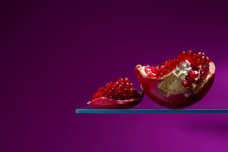 Pomegranate fruit on a glass stand on a purple backgroundの写真素材
