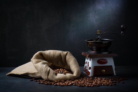 Cup of coffee and coffee grinder, beans on dark backgroundの写真素材
