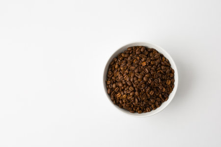Coffee beans in the orange bowl. Top view. Isolated on white background. copy spaceの写真素材