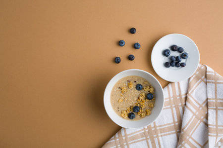 Oatmeal with blueberries in a white bowl on a brown backgroundの写真素材