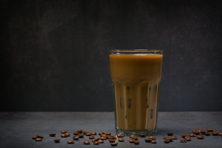 Iced coffee with milk in glass and coffee beans on gray backgroundの写真素材