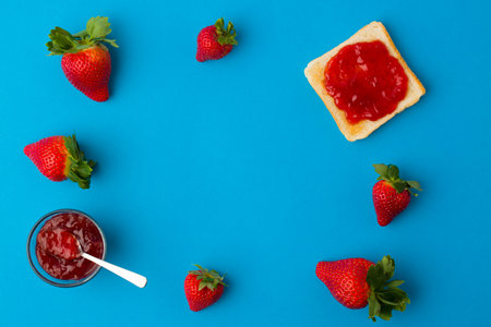 A top view of the strawberry jam-filled bread and strawberry fruit on a blue backgroundの写真素材