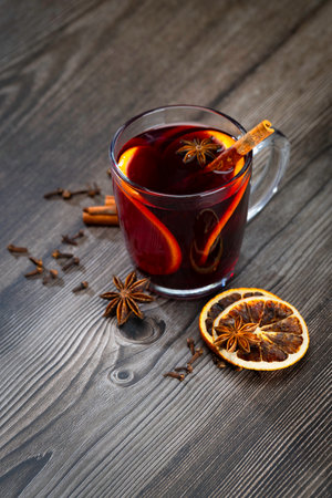 Glass of mulled wine with orange slice. Mulled wine and ingredients on a wooden table. Handheld shootingの写真素材