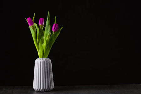 A bouquet of yellow tulips in a vase on the floor.の写真素材