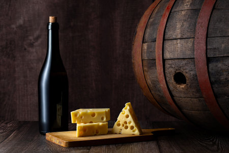 Glass of red wine, cheeses and grapes on old wooden table. dark background.の写真素材