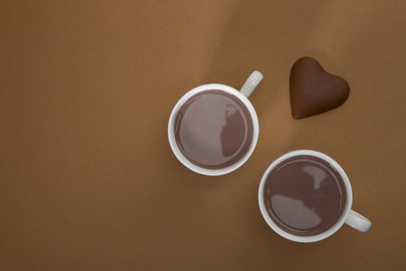 Pieces of bitter chocolate, spoon with cocoa powder and glass of cocoa drink on a brown vintage table.の写真素材