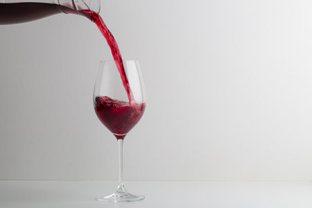 Red wine pouring with white backgroundの写真素材