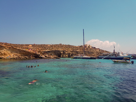 BLUE LAGOON, COMINO, MALTA - AUGUST 09, 2018: Blue Lagoon on a sunny day in Comino, Malta. Some boats are in the Blue Lagoon.のeditorial素材