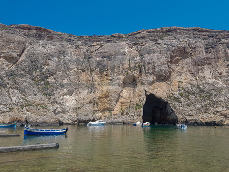 GOZO, MALTA - AUGUST 09, 2018: an arched opening in the rock with boats and people.のeditorial素材