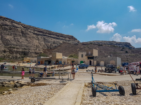 GOZO, MALTA - AUGUST 09, 2018: rocky landscape in Gozo with people, buildings and cars.のeditorial素材