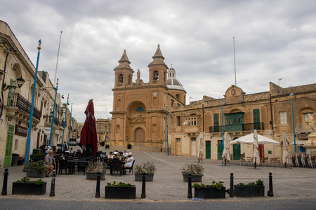 MARSAXLOKK, MALTA - AUGUST 07, 2018: view of the church of Our Lady of Pompeii in the fishing village of Marsaxlokk, Malta. People are seated and relaxing at the tables in the square.のeditorial素材