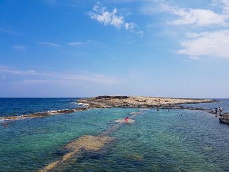 ST. PAUL'S BAY, MALTA - AUGUST 06, 2018: people relaxing on a beautiful rocky beach in St.Paul's Bay on a sunny day.のeditorial素材