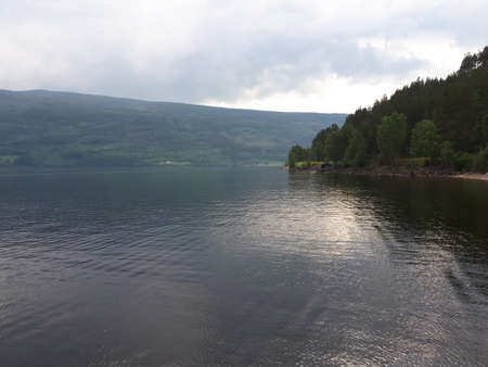 Landscape with cloudy sky over water and mountainsの写真素材