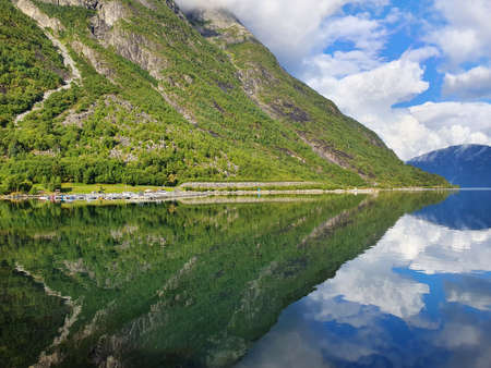 reflection of the sky and mountains in the blue water of the fjord - Eidfjordの写真素材