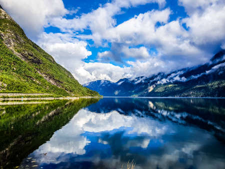 reflection of the sky and mountains in the blue water of the fjord - Eidfjordの写真素材
