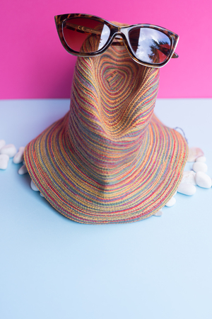 A women's sunglasses on a light blue and fuchsia background. Minimalist nice image that capture the spirit of summer. Acanthocardia tuberculata and other seashells. Horizontal view.の写真素材