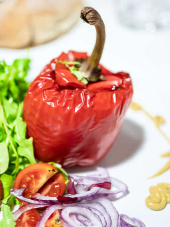 Baked stuffed red peppers with a side of green salad, cherry tomatoes and sliced red onion. Vertical view.の写真素材