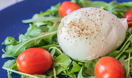 Caprese salad. Healthy meal with tomatoes, mozzarella, spices and fresh rocket. Home made, tasty food. Concept for a tasty and healthy vegetarian meal. Horizontal view.の写真素材
