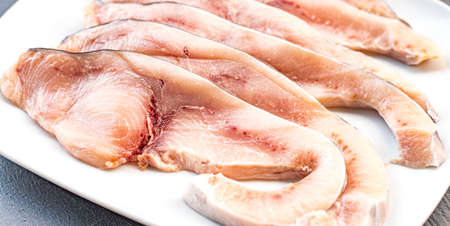 Close-up of various slices of raw swordfish, in a white plate, on a slate table. Tasty food from Italian cuisine and from the Mediterranean sea. Concept for a tasty and healthy meal. Horizontal view.の写真素材