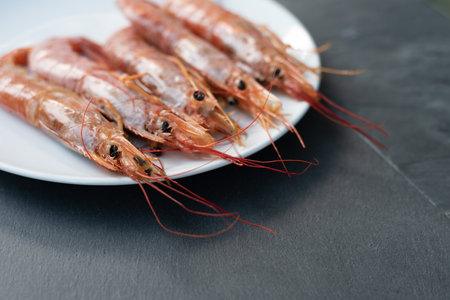 Close up of five giant prawns, in a white plate, on a slate table. Tasty food from Italian cuisine and Mediterranean sea. Concept for a tasty and healthy meal. Horizontal view.の写真素材