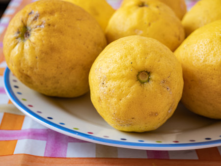 Close up of organic lemons in a colorful dish, on top of a table. Useful as a floral background. Horizontal viewの写真素材