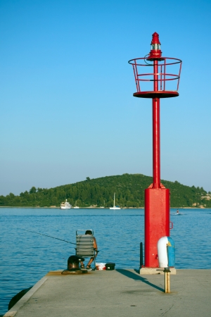 Red lighthouse and a fishing manの写真素材