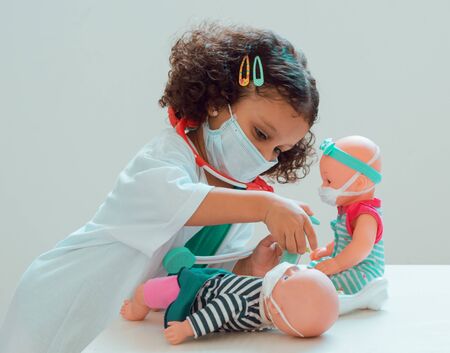 A little girl playing the doctor gives her patient an injection.の写真素材